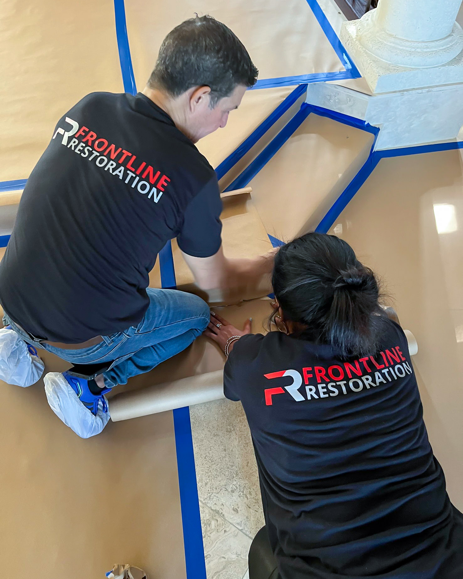 Two Frontline Restoration technicians in branded uniforms working on restoration