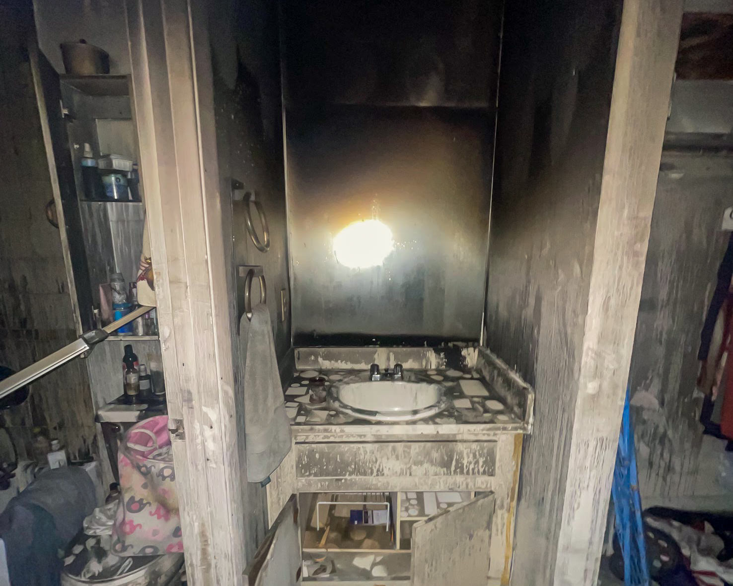 Fire-damaged bathroom — soot-stained mirror and sink